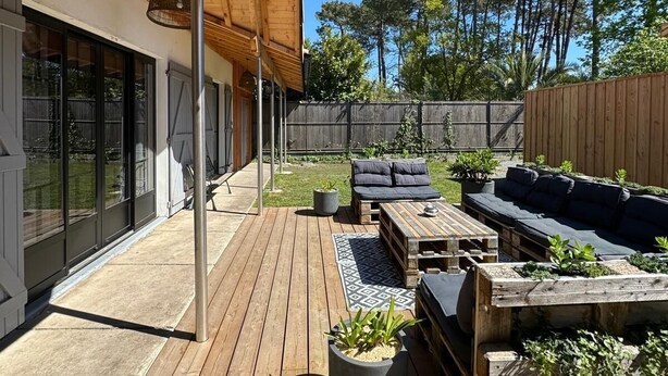 A wooden deck with outdoor furniture, including sofas and a table, surrounded by potted plants. - Arcachon house 900m from the beach. (Andernos-les-Bains)