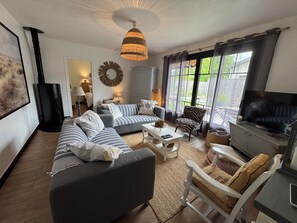 A living room with a sofa set, a television, and a large window with curtains. - House in Arcachon, 900 meters from the beach. (Andernos-les-Bains)