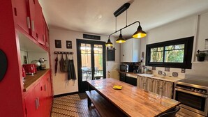 A compact kitchen with a wooden table, a bench, and a red cabinet. - Arcachon house 900m from the beach. (Andernos-les-Bains)