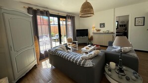 A living room with a sofa, a television, a lamp, and a dining table. - Arcachon house 900m from the beach. (Andernos-les-Bains)