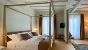 Una habitación de hotel con una cama grande, una zona de estar con una silla y una pequeña mesa.