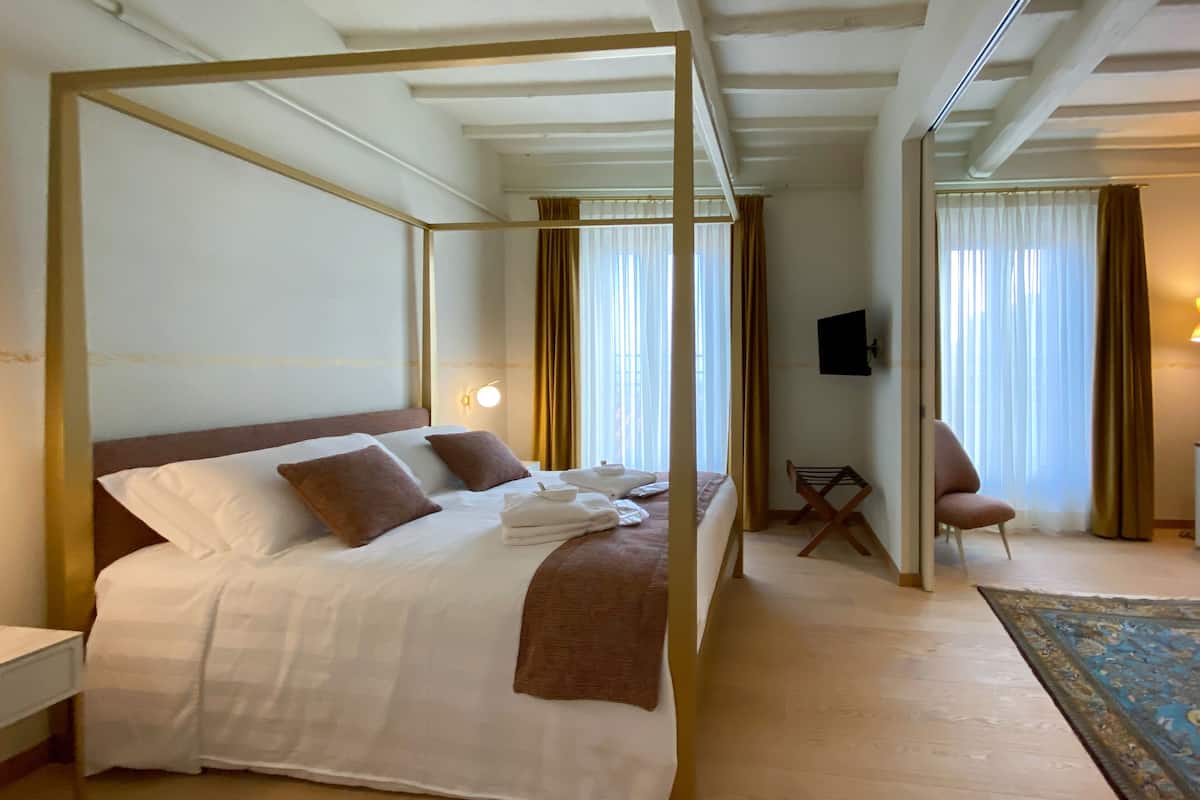 Una habitación de hotel con una cama grande, una zona de estar con una silla y una pequeña mesa.