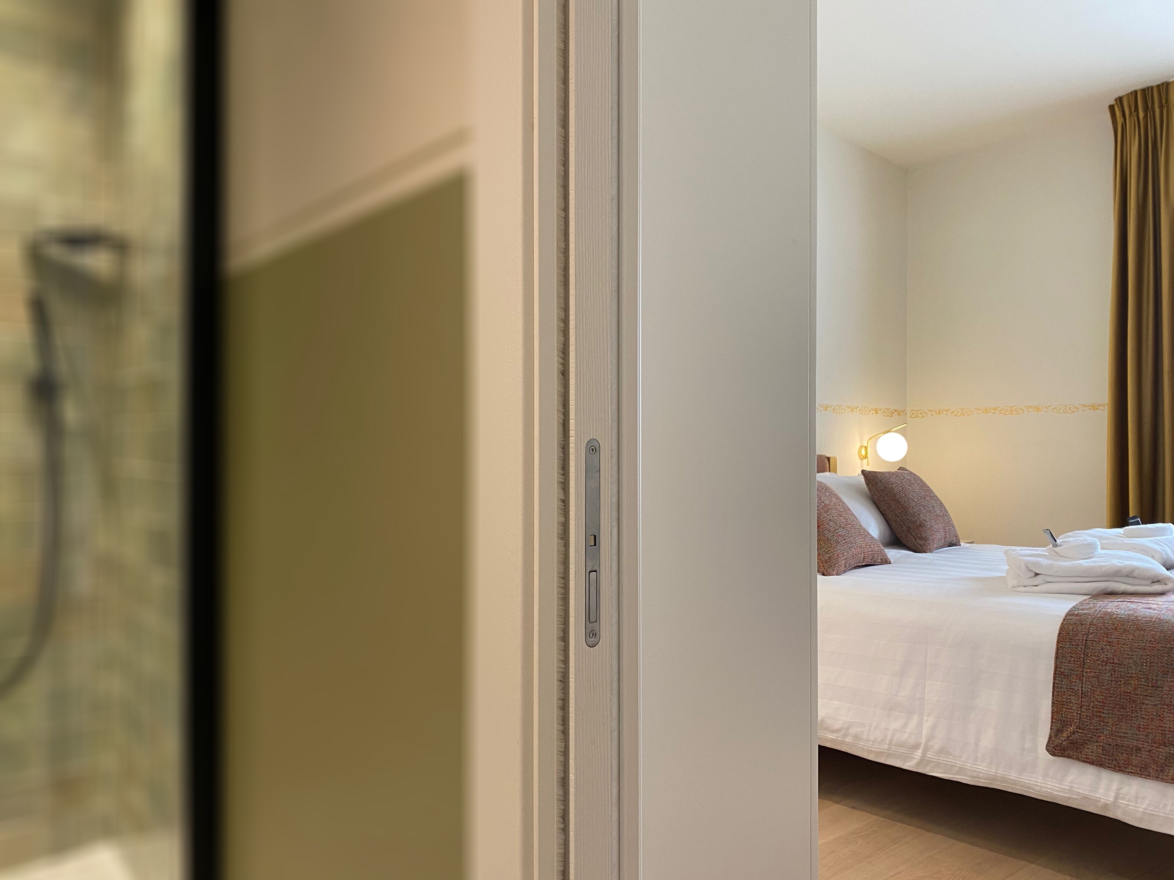 A hotel room with a bed, a bedside table, and a mirror.