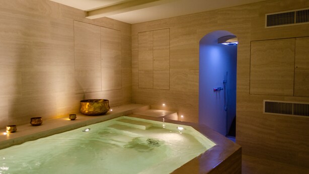 Un cuarto de spa con una bañera grande, zona de ducha y un rincón con velas.