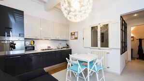 A modern kitchen with black cabinets, a white dining table, and blue chairs. - Pitti Three - Two Bedroom Apartment, Sleeps 4 (Firenze)
