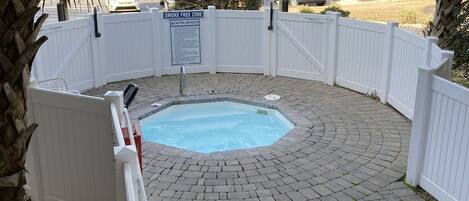 A backyard with a swimming pool surrounded by a white fence, a 'SMOKE FREE ZONE' sign, and a palm tree.
