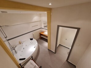 Une salle de bain moderne avec une grande baignoire, un meuble-lavabo en bois et un espace douche.