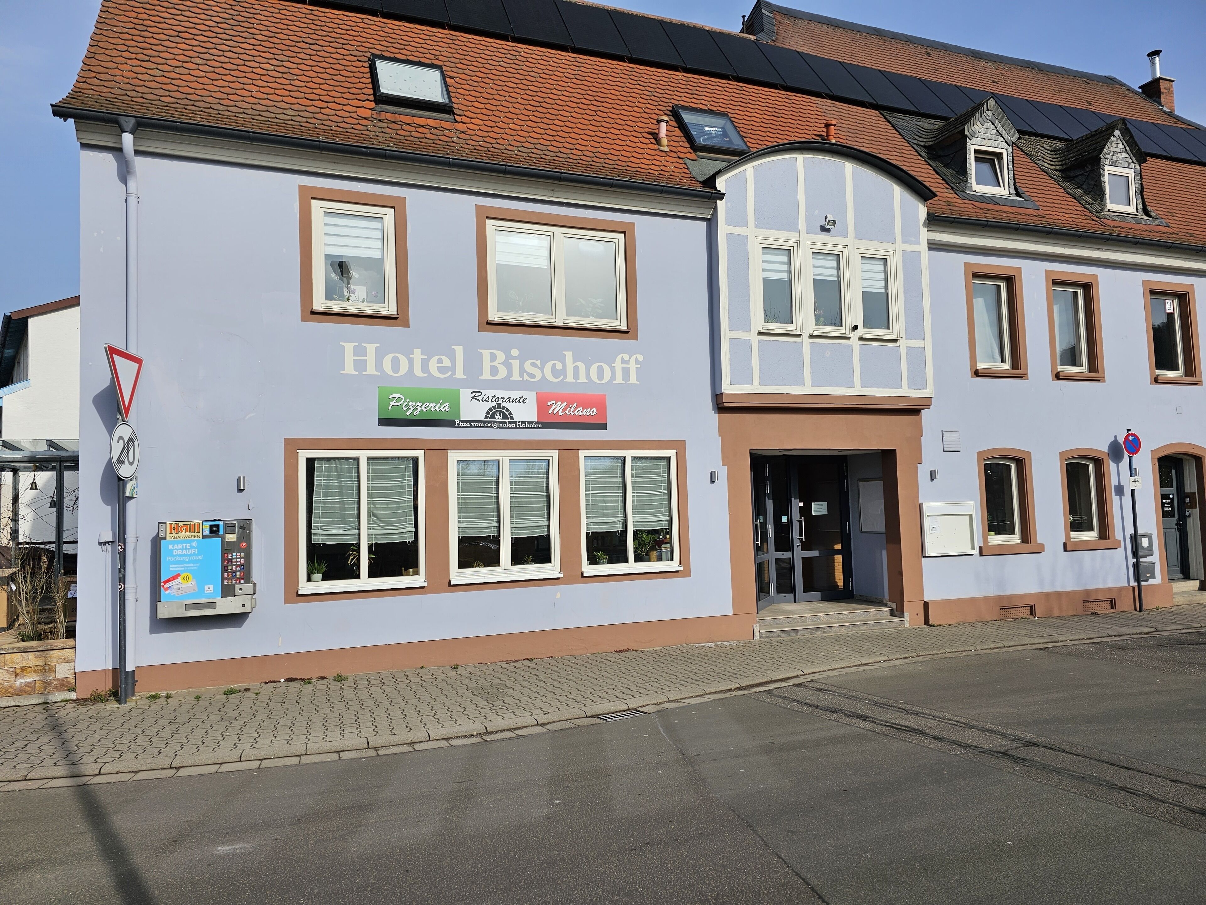 A building with a sign reading "Hotel Bischoff" and a pizzeria sign below it.
