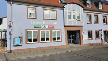 A building with a sign reading "Hotel Bischoff" and a pizzeria sign below it.