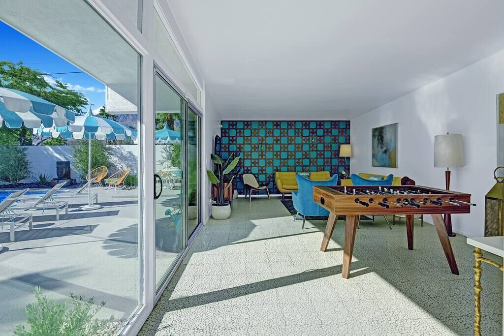 A modern living room with a foosball table, a pool, and a colorful tiled wall.