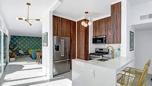 Une cuisine moderne avec des meubles en bois, des appareils électroménagers en acier inoxydable et un îlot central doté de sièges.
