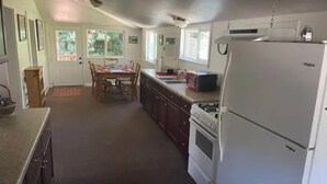 Una cocina equipada con refrigerador, estufa, microondas y mesa de comedor con sillas.