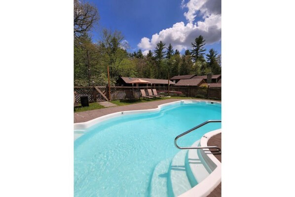 Relax by the serene pool surrounded by lush greenery and comfortable lounge chairs.