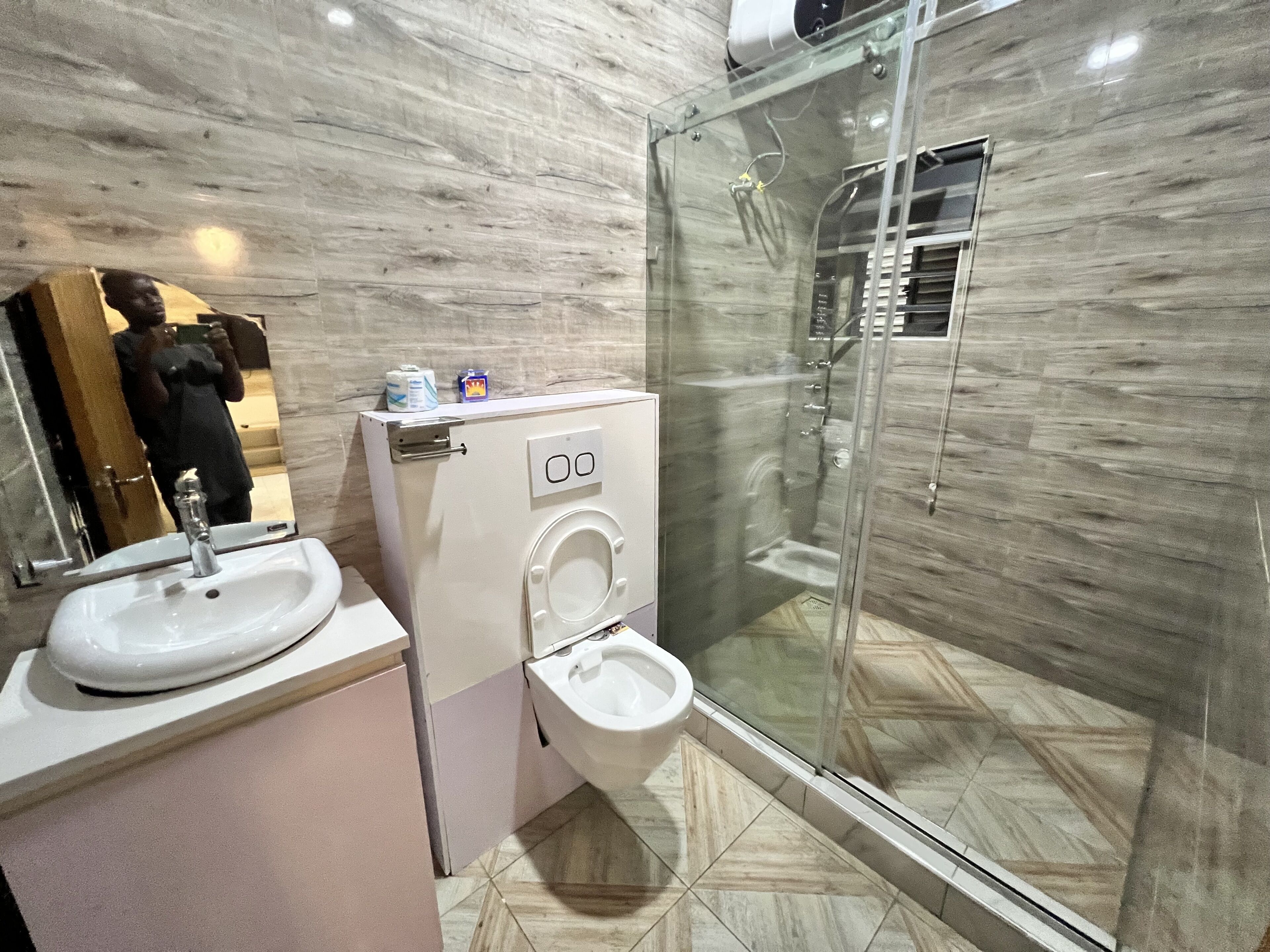 A modern bathroom with a glass-enclosed shower, a toilet, and a sink.