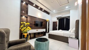 Ein modernes Hotelzimmer mit einem großen Bett, einer Couch, einem an der Wand befestigten Fernseher und einem kleinen Tisch.