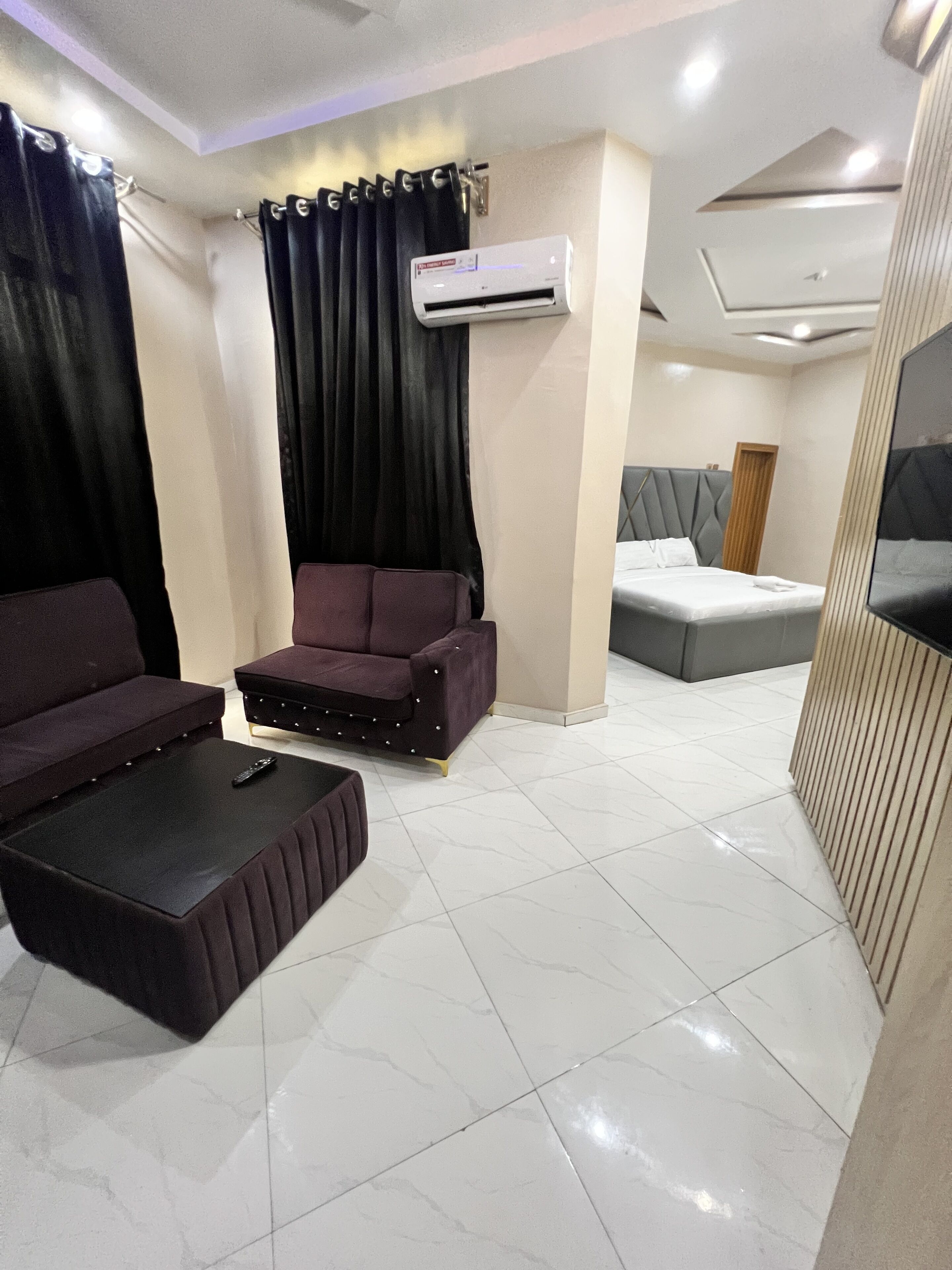 Uma sala de estar moderna com sofá, mesinha, cama e ar condicionado.