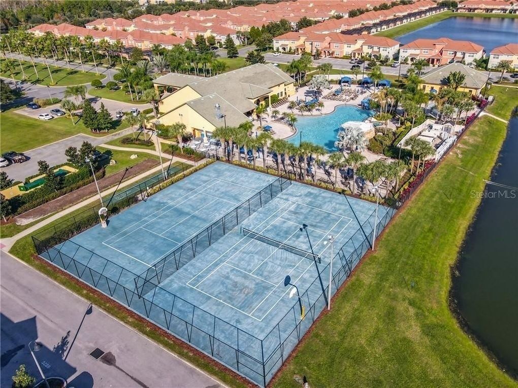 An aerial view of a resort with a large tennis court, a swimming pool, and a water park.