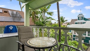 A balcony with a table and chairs, solar panels on the building, and lush greenery.