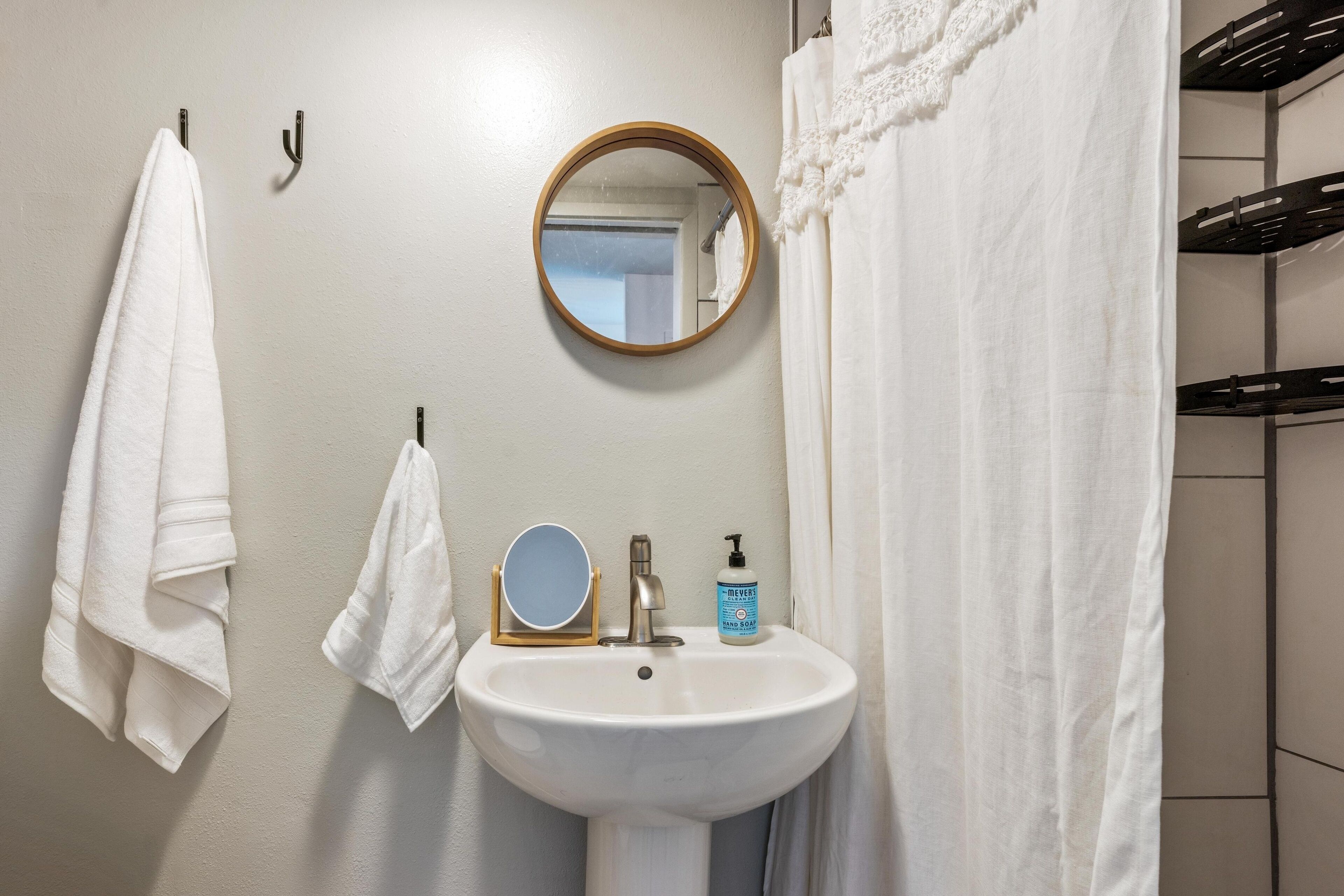 A bathroom with a white sink, a round mirror, and a towel rack.