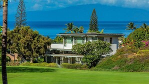 A modern house with a large lawn and a view of the ocean.