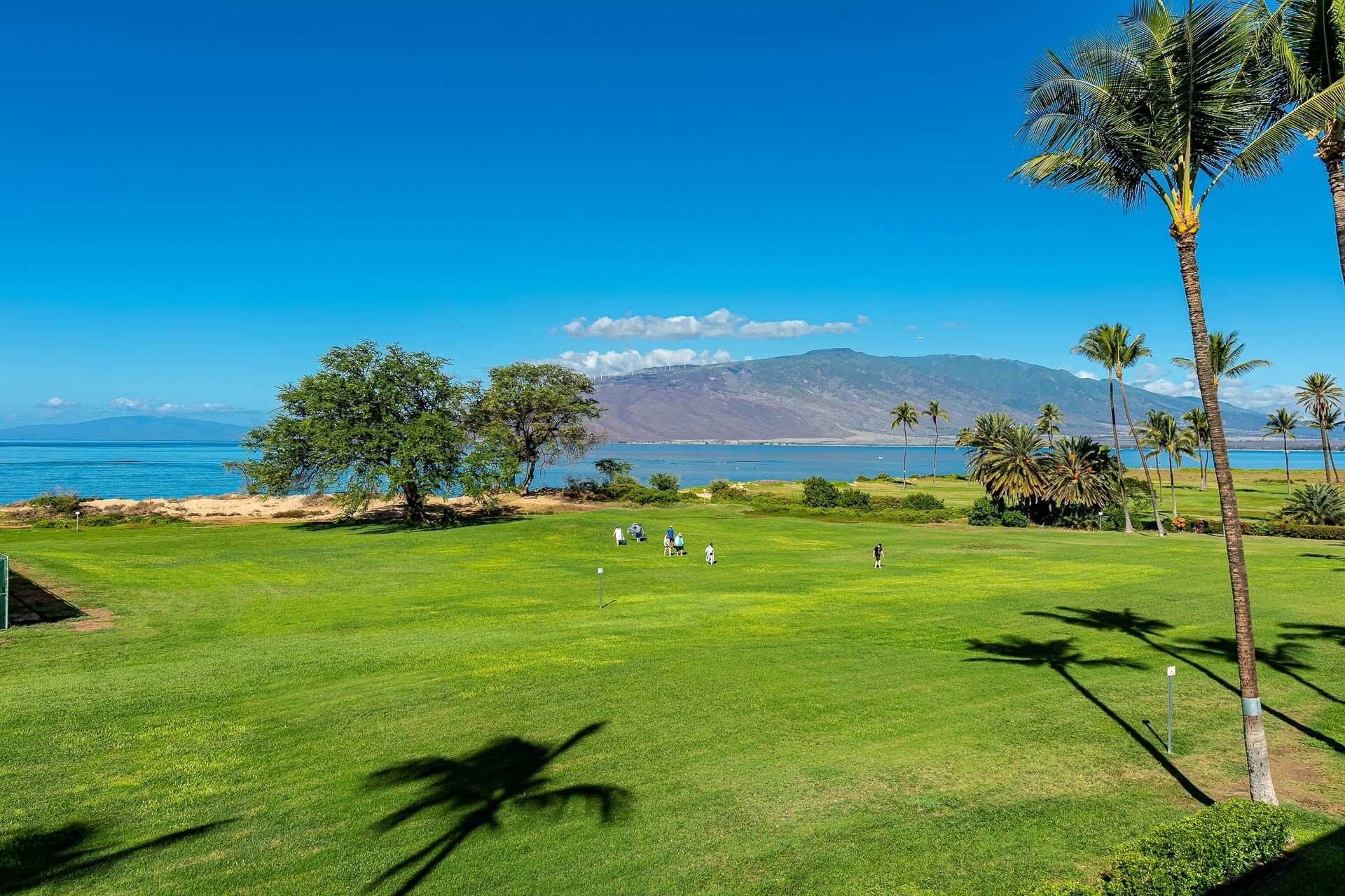 Un parcours de golf offrant une vue sur l’océan et les montagnes en arrière-plan.