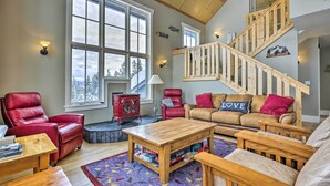 Un salon spacieux avec un escalier en bois, des fauteuils en cuir, une table basse en bois et une cheminée.