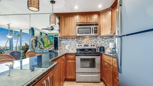 Une cuisine moderne avec des meubles en bois, un four en acier inoxydable et un grand îlot central doté d’un plan de travail en verre.
