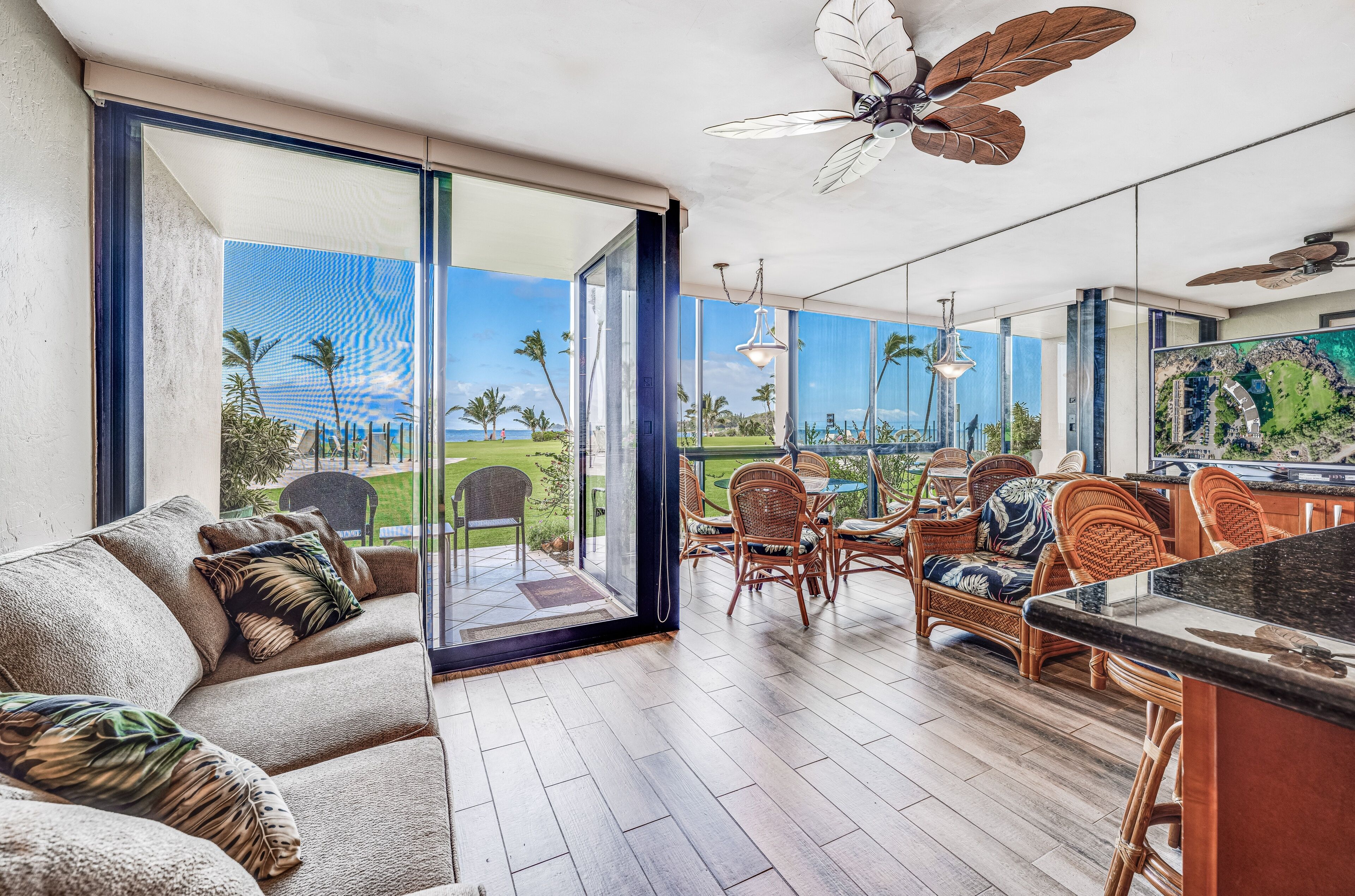 A spacious room with a large sliding glass door leading to a balcony, furnished with a sofa, chairs, and a dining table.