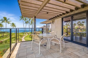 A covered outdoor seating area with a view of the ocean and palm trees. - Wailea Elua, #1404 2 Bedroom Condo by RedAwning (Kihei)