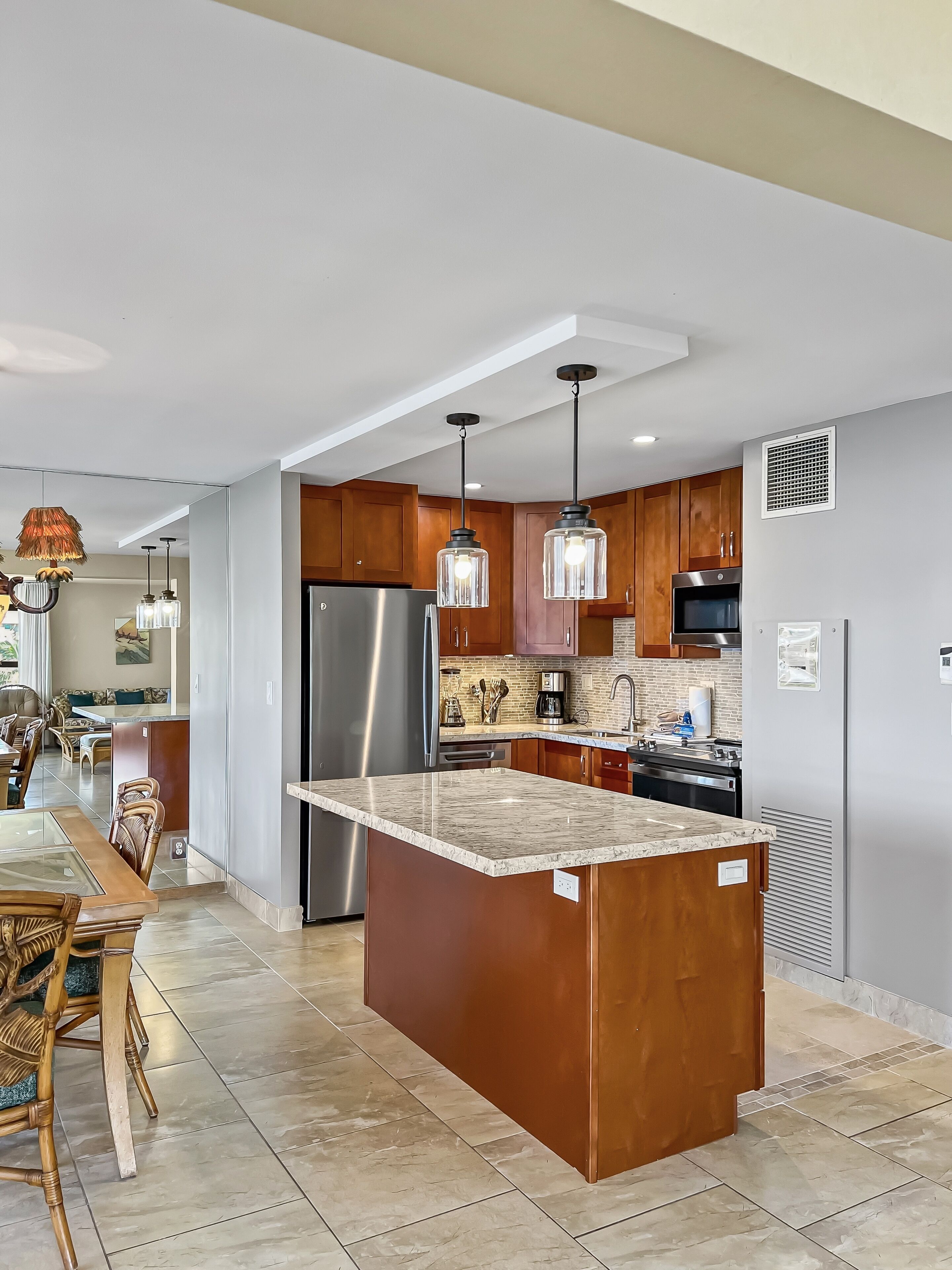 A modern kitchen with a central island, stainless steel appliances, and pendant lighting.