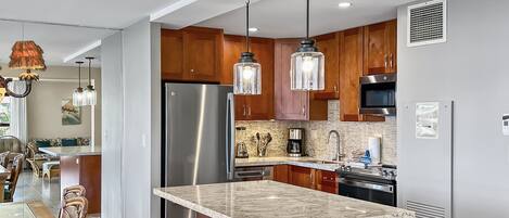 A modern kitchen with a central island, stainless steel appliances, and pendant lighting.