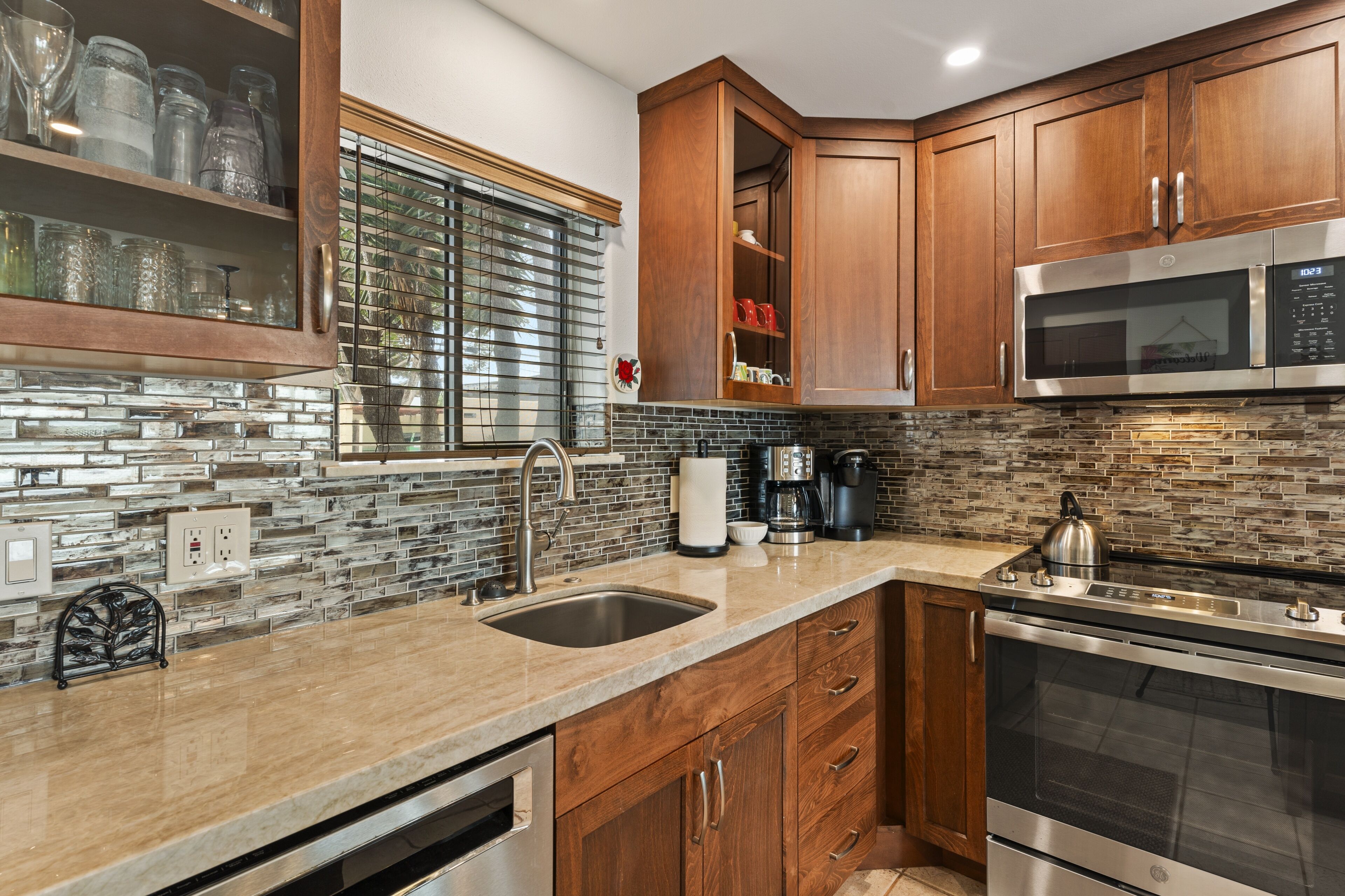 A modern kitchen with wooden cabinets, a stainless steel microwave, and a built-in oven.
