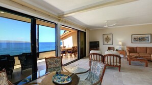 A spacious living area with a large glass table, comfortable seating, and a view of the ocean. - Makena Surf, #f-202 2 Bedroom Condo by RedAwning (Kihei)