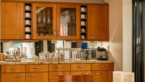 A kitchen with wooden cabinets, a countertop with various kitchen items, and a dining area with a table and chairs. - Makena Surf, #g-301-302 4 Bedroom Condo by RedAwning (Kihei)