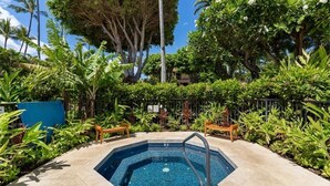 Une piscine entourée d’une végétation luxuriante et de palmiers.