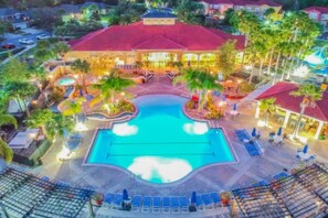 Un resort con piscina central, zonas de descanso y un edificio de techo rojo.
