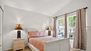 A bedroom with a bed, bedside tables, a window with curtains, and a view of the outside. - Park Villa 4 Bedroom Villa by RedAwning (Davenport)