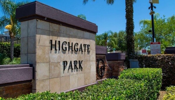A sign for Highgate Park with a stone facade and a bicycle wheel design.