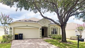A single-story house with a garage, a brick driveway, and a large tree in front. - Park Villa 4 Bedroom Villa by RedAwning (Davenport)