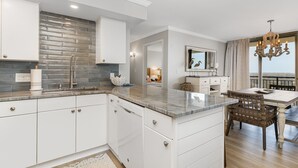Uma cozinha moderna com armários brancos, bancada de granito e painel decorativo.