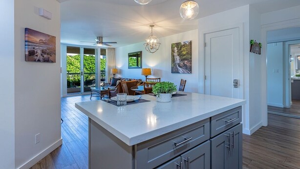 A modern kitchen with a large island, pendant lighting, and artwork on the walls. - Maui Banyan by Coldwell Banker Island Vacations (Kihei)