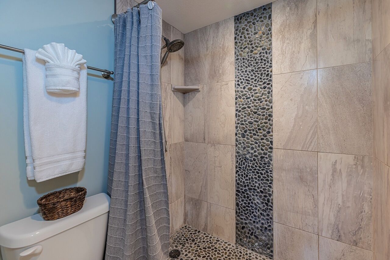 Une salle de bain avec une douche, des toilettes et un porte-serviettes.