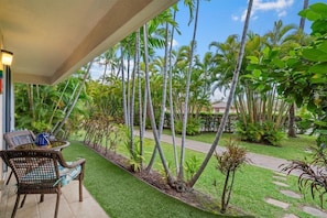 Un espace extérieur abrité, aménagé avec des sièges, un chemin et une variété de plantes tropicales.