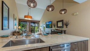 Una cocina moderna con una isla grande, electrodomésticos de acero inoxidable e iluminación colgante.