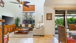 A living room with a television, sofa, coffee table, and a ceiling fan. - Big Island Fairways At Mauna Lani 1701 2 Bedroom Condo (Kamuela)