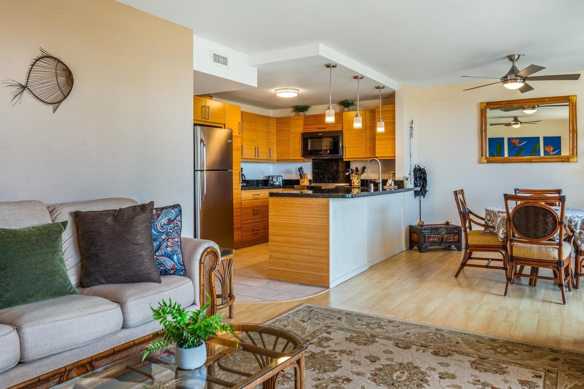 A modern kitchen with wooden cabinets, a central island, and a dining area with a table and chairs.
