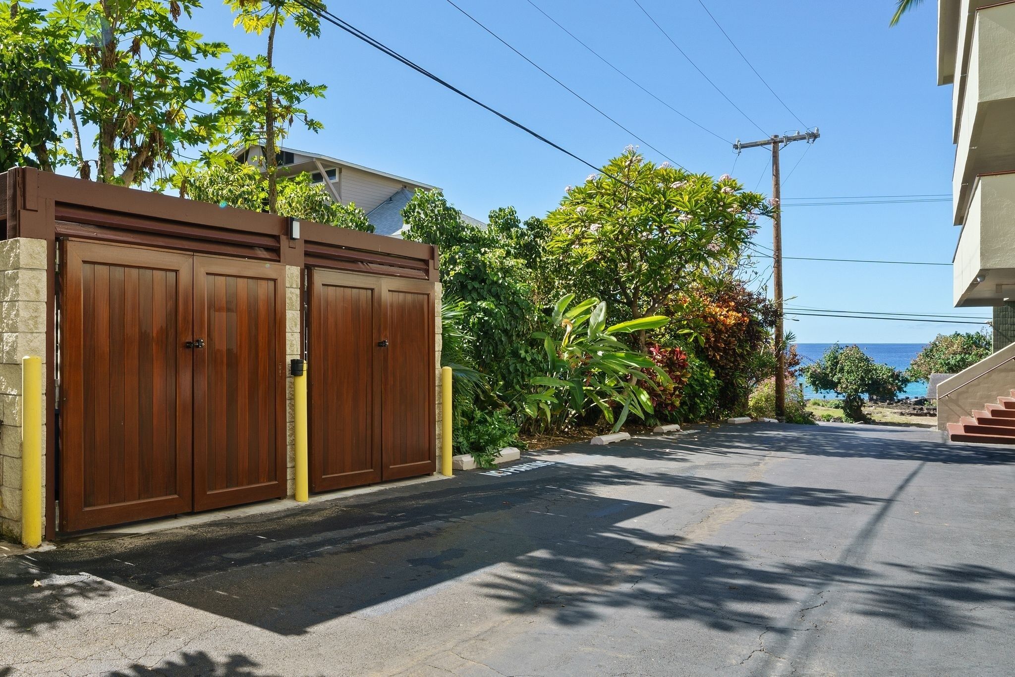 A gated driveway leading to a building with a view of the ocean.