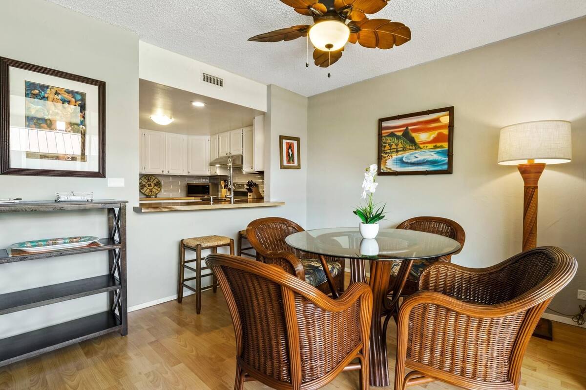 Ein Essbereich mit Korbstühlen, einem Glastisch und einem Deckenventilator.