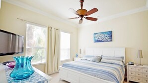 A bedroom with a bed, a ceiling fan, a TV, and a window with curtains. - Reunion Retreat 3 Bedroom Home by RedAwning (Kissimmee)