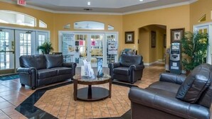 A lobby with leather sofas, a coffee table, and a reception area with a counter and informational posters. - Sunshine Villa 5 Bedroom Villa by RedAwning (Kissimmee)